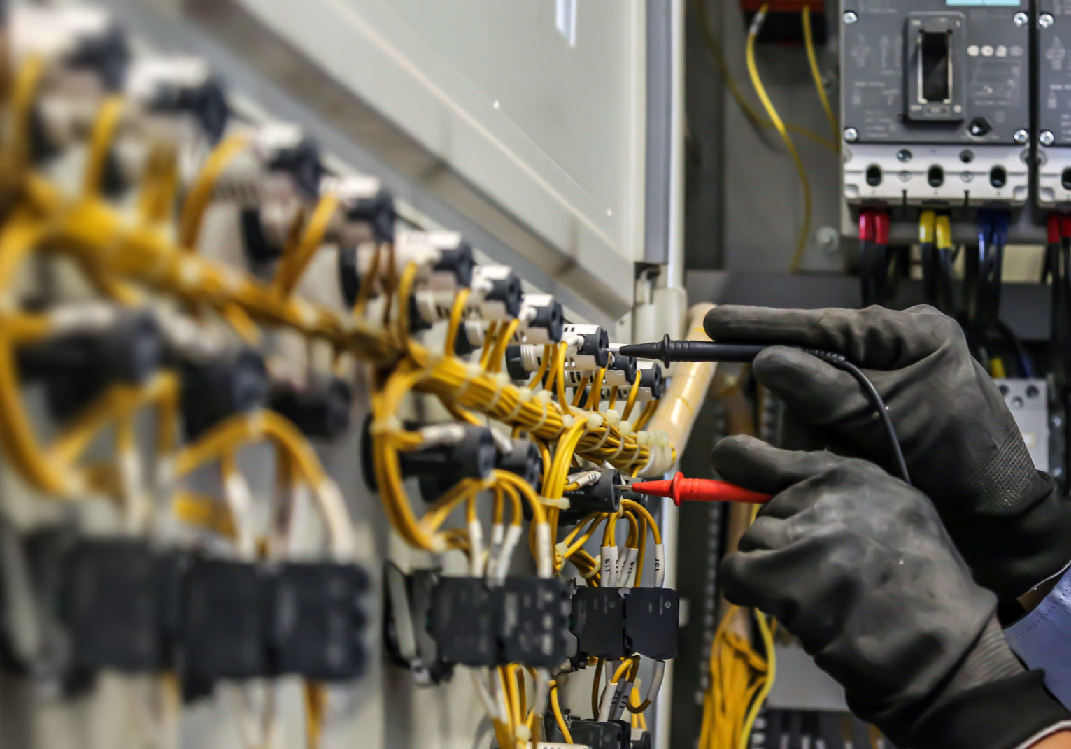 Electrical engineer using measuring equipment to checking electric current voltage at circuit breaker and cable wiring system for maintenance in main power distribution board.